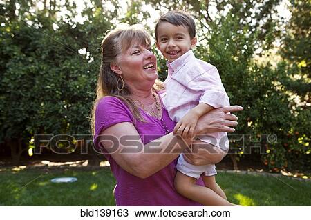 Stock Image - Grandmother holding grandson in backyard. Fotosearch