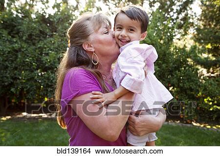 Grandmother kissing grandson in backyard View Large Photo Image Picture - Grandmother kissing grandson in backyard. Fotosearch