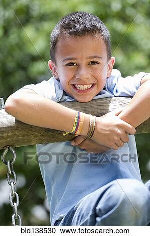 Stock Image - Hispanic boy playing at playground. Fotosearch