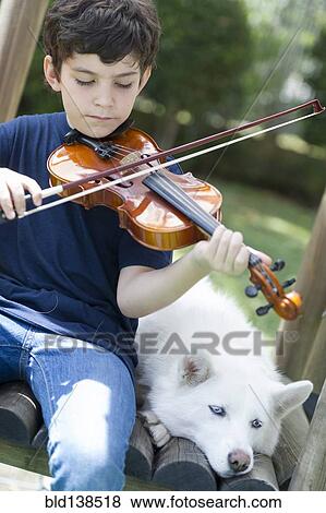 Stock Photo - Hispanic boy playing violin with dog. Fotosearch
