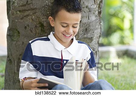 Stock Image - Hispanic boy reading book. Fotosearch