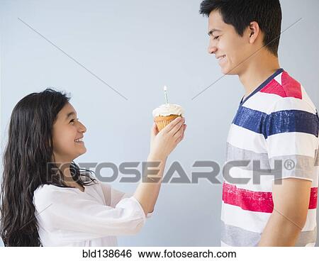 Stock Photograph - Hispanic brother and sister celebrating birthday with cupcake. Fotosearch