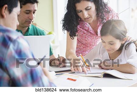 Picture - Hispanic family doing homework together at table. Fotosearch