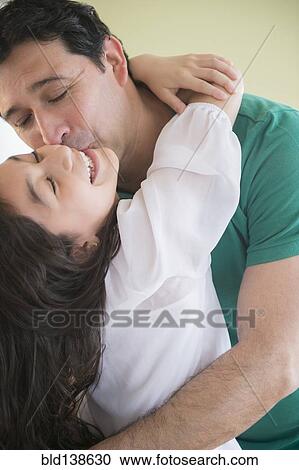 Stock Image - Hispanic father kissing daughter on cheek. Fotosearch