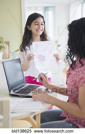 Hispanic girl proudly showing drawing to mother View Large Photo Image Stock Photography - Hispanic girl proudly showing drawing to mother. Fotosearch