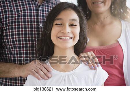 Stock Image - Hispanic girl smiling with parents. Fotosearch