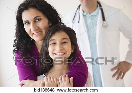 Stock Photo - Hispanic mother and daughter smiling with doctor. Fotosearch