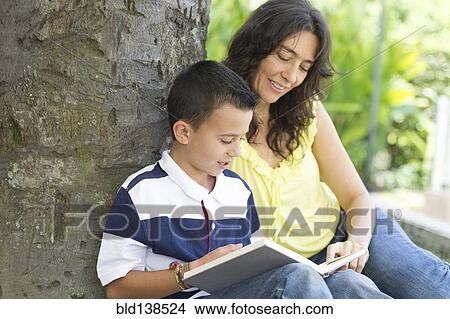 Picture - Hispanic mother and son reading book. Fotosearch