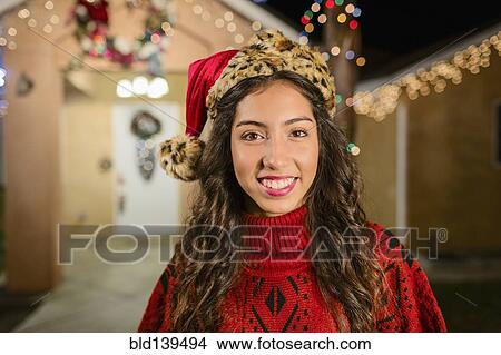 Hispanic woman smiling outside house decorated with string lights View Large Photo Image Picture - Hispanic woman smiling outside house decorated with string lights. Fotosearch