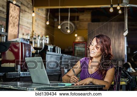 Hispanic woman using laptop in coffee shop View Large Photo Image Picture - Hispanic woman using laptop in coffee shop. Fotosearch
