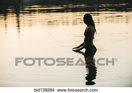 Picture - Korean woman standing in still lake. Fotosearch