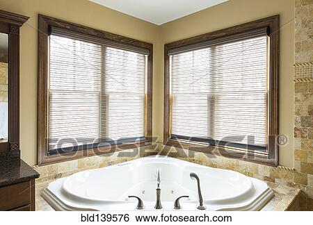 Stock Photograph - Luxury bathtub and windows in corner of modern bathroom. Fotosearch