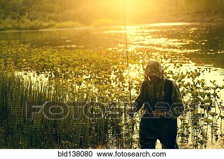 Stock Image - Mari fisherman carrying fishing rod at lake. Fotosearch