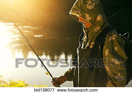 Stock Photo - Mari man holding fishing rod at lake . Fotosearch