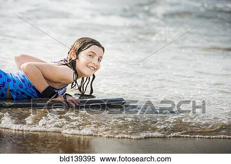 Mixed race girl riding boogie board at beach View Large Photo Image Stock Photography - Mixed race girl riding boogie board at beach. Fotosearch