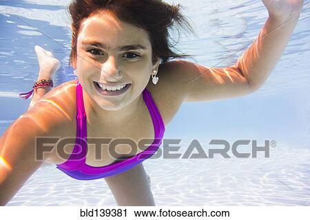 Stock Image - Mixed race girl swimming underwater. Fotosearch