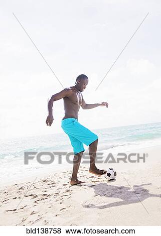 Mixed race man playing with soccer ball on beach View Large Photo Image Stock Photo - Mixed race man playing with soccer ball on beach. Fotosearch