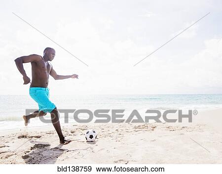 Mixed race man playing with soccer ball on beach View Large Photo Image Stock Photo - Mixed race man playing with soccer ball on beach. Fotosearch
