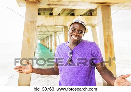 Mixed race man smiling under pier on beach View Large Photo Image Stock Image - Mixed race man smiling under pier on beach. Fotosearch