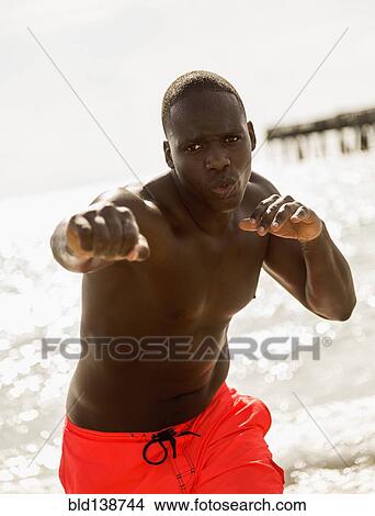 Picture - Mixed race man training on beach. Fotosearch