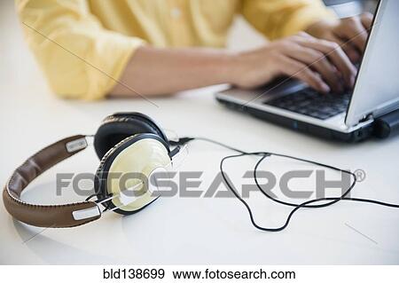 Mixed race man using laptop with headphones View Large Photo Image Stock Photo - Mixed race man using laptop with headphones. Fotosearch