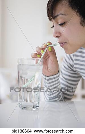 Picture - Mixed race woman drinking water with straw. Fotosearch