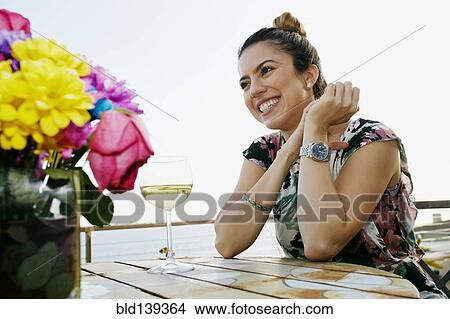 Picture - Mixed race woman drinking wine at waterfront. Fotosearch