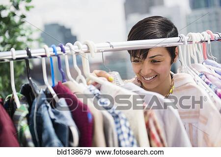 Mixed race woman examining clothing on rack View Large Photo Image Stock Photo - Mixed race woman examining clothing on rack. Fotosearch