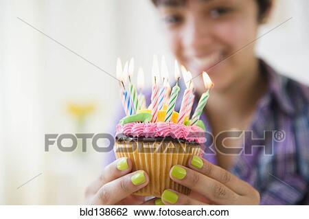 Mixed race woman holding cupcake with birthday candles View Large Photo Image Stock Image - Mixed race woman holding cupcake with birthday candles. Fotosearch