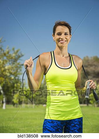 Stock Photo - Mixed race woman holding jump rope in park. Fotosearch