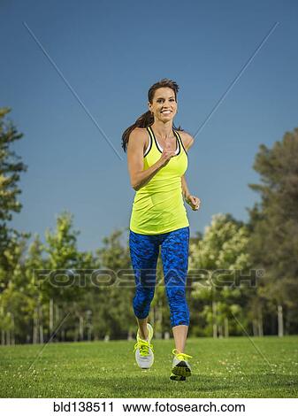 Stock Image - Mixed race woman jogging in park. Fotosearch