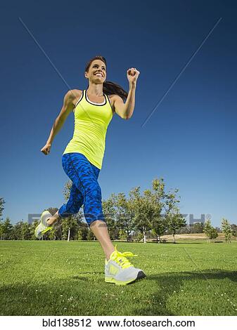Stock Image - Mixed race woman jogging in park. Fotosearch