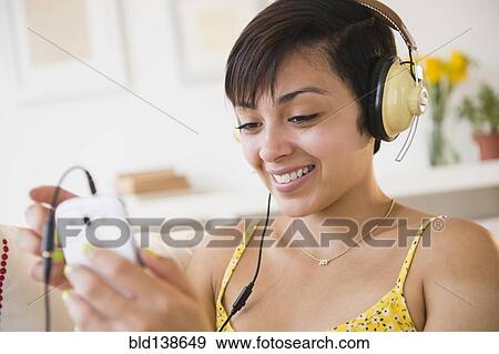 Stock Photo - Mixed race woman listening to headphones. Fotosearch