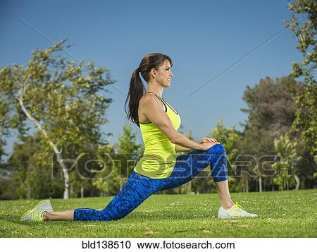 Stock Image - Mixed race woman stretching in park. Fotosearch