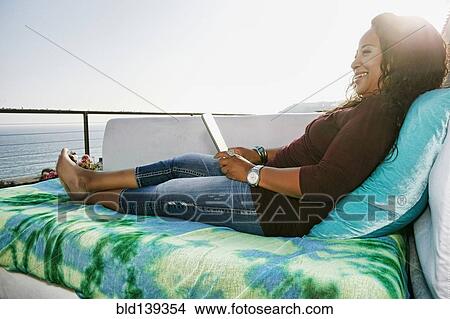 Picture - Mixed race woman using digital tablet at waterfront. Fotosearch