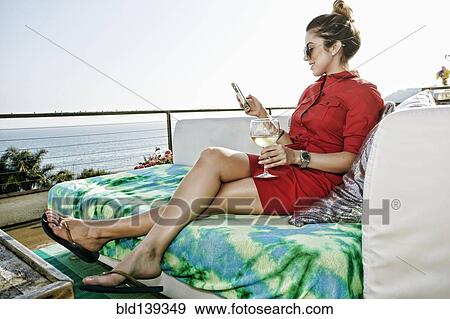 Mixed race woman with white wine and cell phone at waterfront View Large Photo Image Stock Photo - Mixed race woman with white wine and cell phone at waterfront. Fotosearch