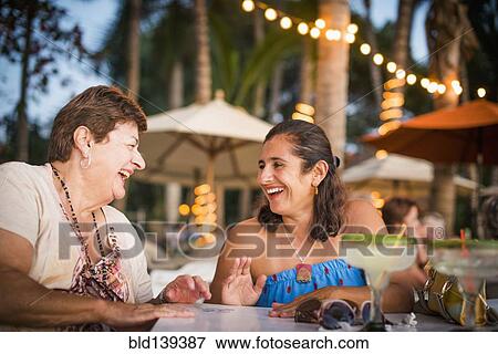 Mother and daughter laughing at outdoor table View Large Photo Image Stock Photo - Mother and daughter laughing at outdoor table. Fotosearch