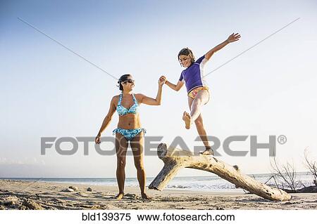 Mother and daughter playing on log on beach View Large Photo Image Stock Photography - Mother and daughter playing on log on beach. Fotosearch
