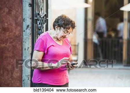 Older woman using cell phone in city View Large Photo Image Picture - Older woman using cell phone in city. Fotosearch