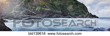 Stock Photo - Panoramic view of waves washing up on rocky beach. Fotosearch