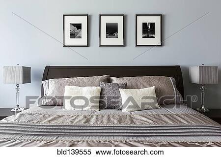 Stock Photography - Pictures, lamps and bed in modern bedroom. Fotosearch