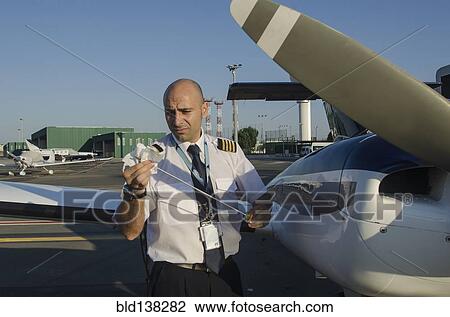 Stock Image - Pilot checking oil in airplane. Fotosearch
