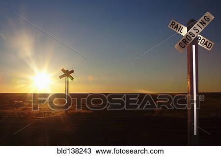 Stock Image - Railroad crossing sign on remote road at sunset. Fotosearch