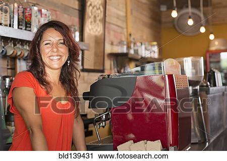 Stock Image - Smiling Hispanic woman working in coffee shop. Fotosearch