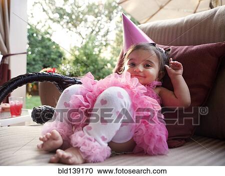 Stock Image - Smiling mixed girl wearing party hat. Fotosearch