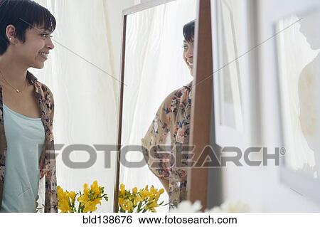Smiling mixed race woman admiring herself in mirror View Large Photo Image Stock Photograph - Smiling mixed race woman admiring herself in mirror. Fotosearch
