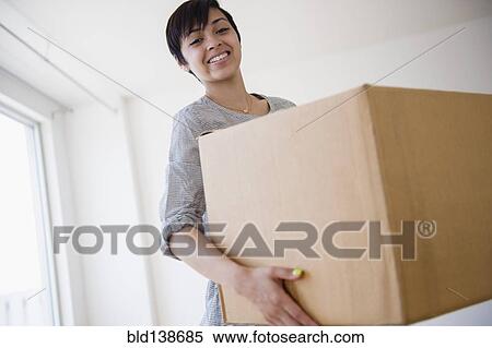 Stock Photography - Smiling mixed race woman carrying cardboard box. Fotosearch