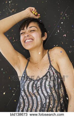Stock Image - Smiling mixed race woman dancing in confetti. Fotosearch