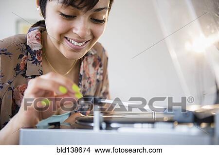 Smiling mixed race woman playing vinyl record View Large Photo Image Picture - Smiling mixed race woman playing vinyl record. Fotosearch