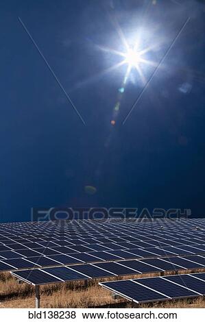 Stock Photo - Sun shining over field of solar panels. Fotosearch